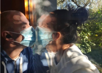 Deputeti i PS-së infektohet me Covid, puth bashkëshorten pas xhamit