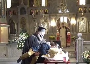 Pamje të frikshme nga Greqia, prifti ngre fëmijën të puthë priftin tjetër që ka ndërruar jetë nga Covid (VIDEO)