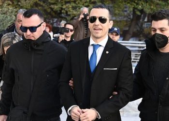 Me pranga në duar dhe i buzëqeshur, anëtari i “Agimit të Artë” del nga burgu për t’u betuar në bashkinë e Athinës (FOTO)