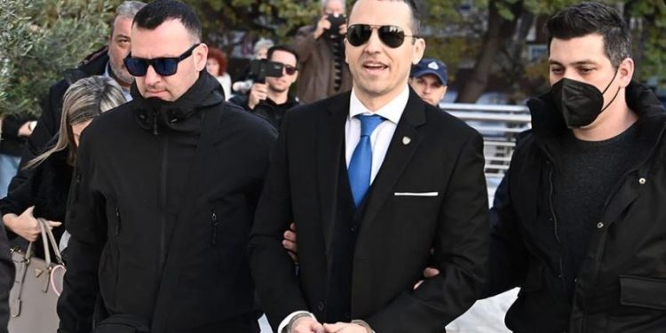 Me pranga në duar dhe i buzëqeshur, anëtari i “Agimit të Artë” del nga burgu për t’u betuar në bashkinë e Athinës (FOTO)