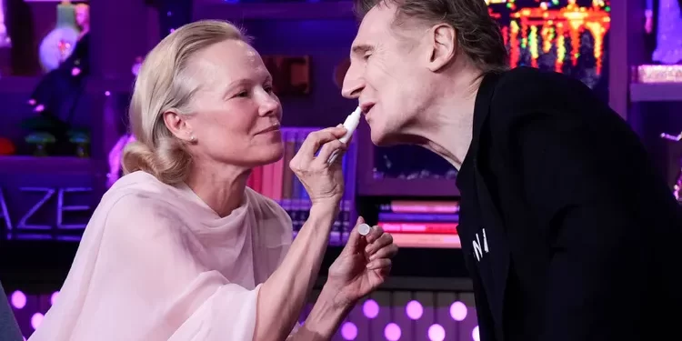 Flirt live në studio! Pamela Anderson “tundon” Liam Neeson me buzëkuqin e saj